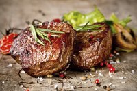 Small steak bites with rosemary garnish.