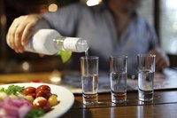 Bartender pouring three shots of vodka.