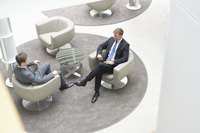 Business people are sitting in chairs having a discussion.