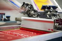 A machine using ink to make a screen print.