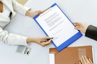 An overhead view of two businesspeople signing a contract.
