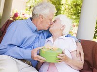 Mature couple holding a present and kissing.