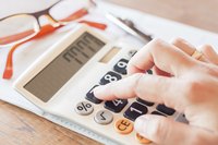 Close-up of woman calculating salary on a calculator.