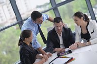 A manager meets with three co-workers in a modern office