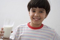 A boy holding a tall glass of milk.