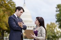 Woman asking man survey questions off of clipboard.