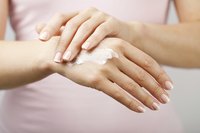 A close-up of a woman applying udder balm to her hands.