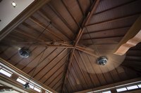 Two spinning ceiling fans in a the peak of a wooden ceiling.