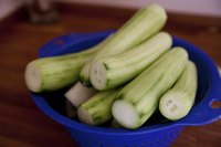 A colander of peeled cucumbers on a table.