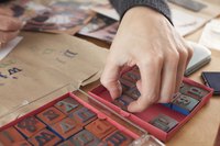 A man applying ink with letter stamps onto a piece of kraft paper.