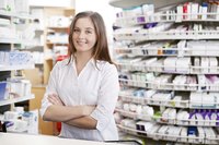Pharmacist standing in front of a shelf of prescrition medications.