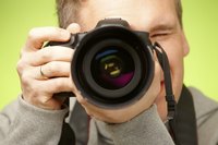 Close-up of photographer holding up DSLR camera with large lens