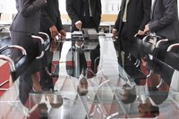 Business men are gathered around a table.