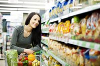 Woman with cart shopping for groceries.