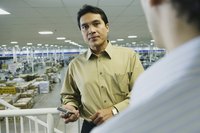 A business man is standing in a manufacturing facility.