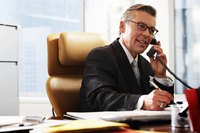 Businessman talking on a phone and taking notes.