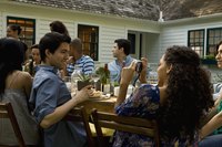 A woman taking photos at an outdoor table in the backyard with a group of friends and family.