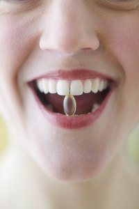A woman is holding a supplement between her teeth.