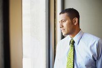 A contemplative businessman looking out of an office window.