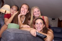 Teen girls are watching TV together.