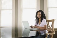 A smiling woman is typing at her desk.