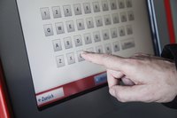 Close-up of a hand typing on a kiosk menu screen
