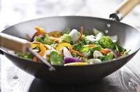 Fresh vegetables in a wok on a wooden table.