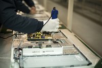A close-up of a technician working manually on an assembly line.