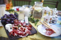 Prosciutto, grapes and cheese on a tuscan picnic spread.