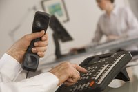 Man picking up office phone and dialing a number.