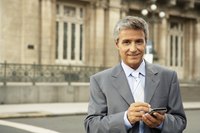 Mature businessman working on phone with charming smile on face.