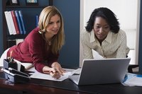 Two business professional looking at a laptop computer screen.