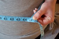 Woman using a tape measure to measure her waist.