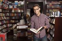 A young man holds an open book in a book store