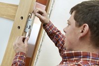 Locksmith installing a lock in a door.