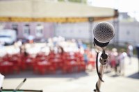 A microphone is set in front of chairs that are beneath a tent.