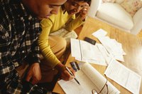 A couple looking at an invoice and an accounting ledger on the coffeetable at home.