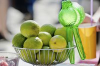 A bowl of limes and a squeezer in a bowl on a counter.