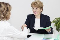 A manager gives her employee a promotion.