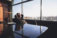 Business executive relaxing and looking out of an office window.