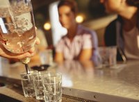 Bartender pouring three shots of alcohol for patrons