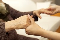 Young woman's hands holding an elder woman's hands.