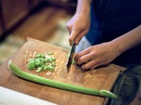 A chef chops celery on a cutting board.