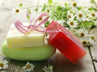 Three bars of soap on a table with fresh daisies.