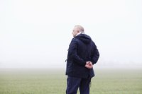A senior stops to reflect while taking a stroll outside on a foggy morning.