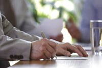 A man is filling out a form on his desk.
