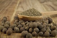 Allspice on table beside spoonful of grounded allspice