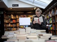 Woman reading book in bookstore.