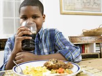 A boy is drinking a glass of soda.