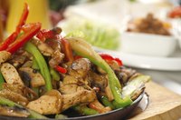 Chicken fajitas sizzling on a cast iron plate with accoutrements.